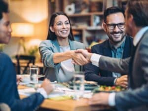 Group gathering around table-two shaking hands