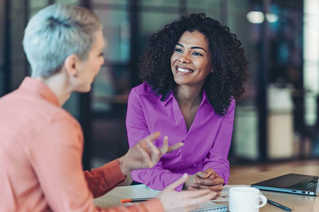 Happy business woman listening to a discussion in an office boardroom. Business professional sitting in a meeting with his colleagues.