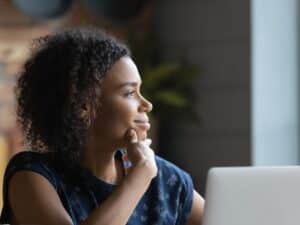 A woman gazing out the window by her laptop